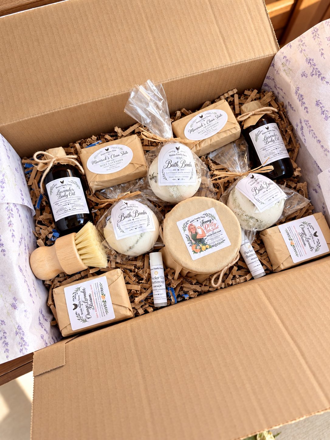 An open gift box of Ristau Family Farm soaps, bath bombs, body oil and lip balm, packed to ship